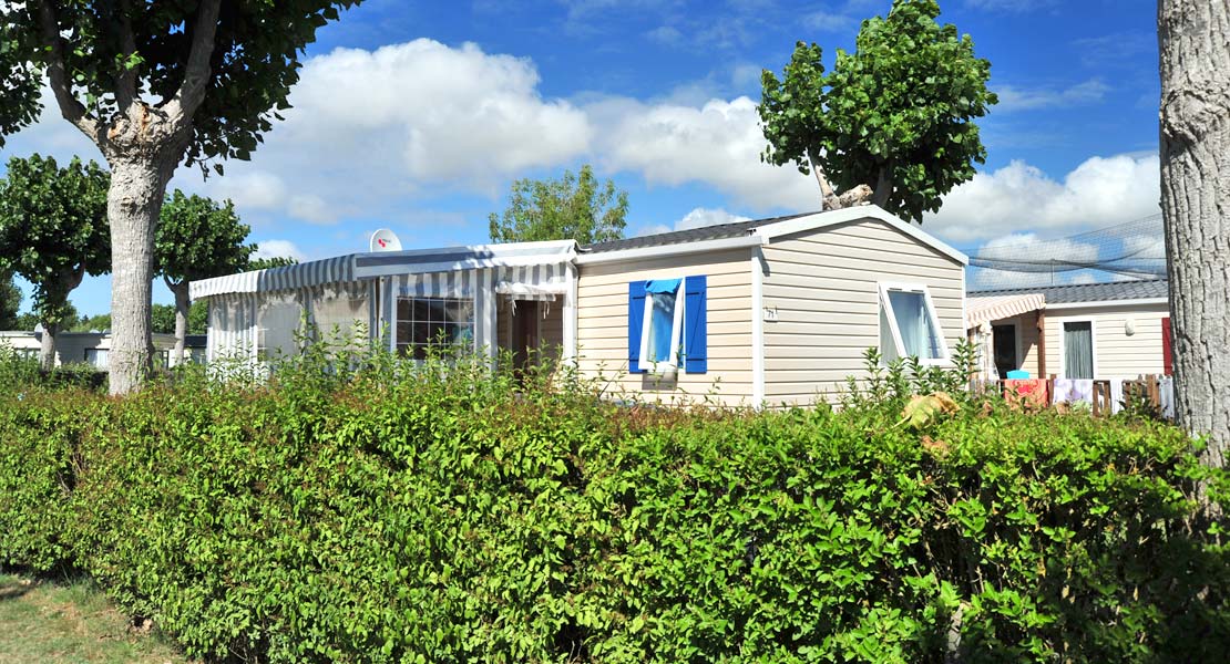 Mobile home for rent surrounded by hedges in the shade of tall trees in Saint-Hilaire