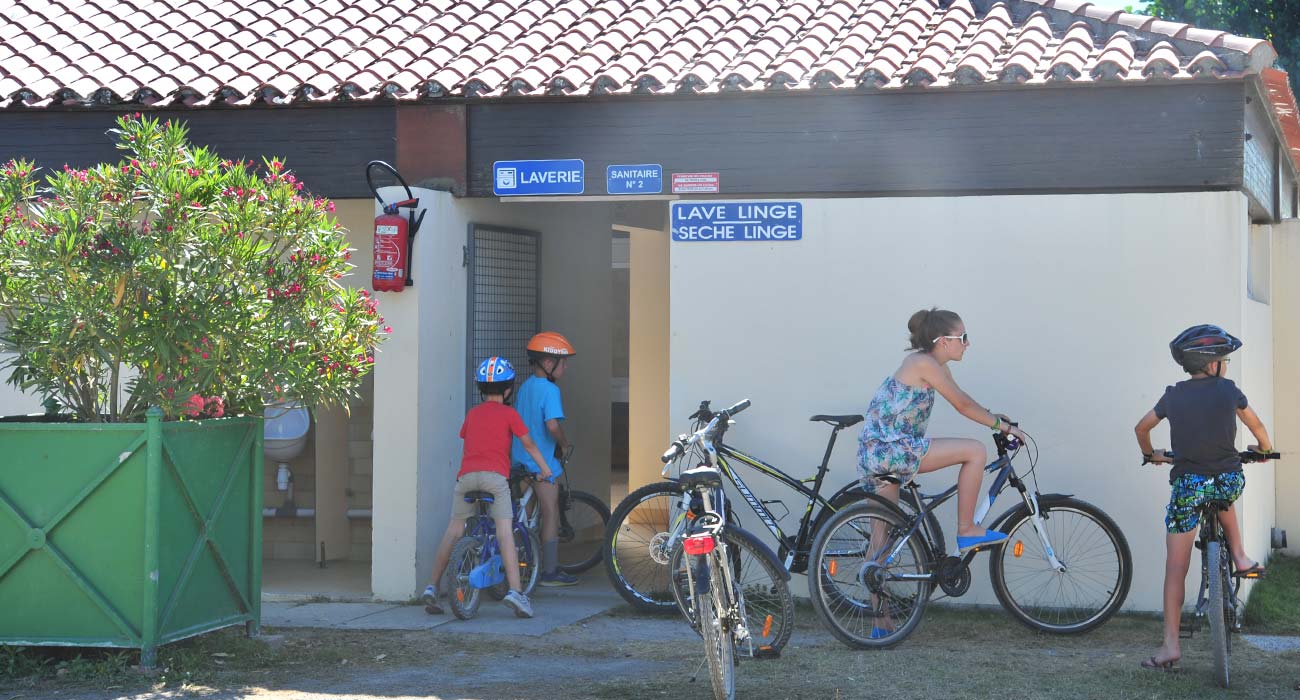 Kinderen op de fiets voor de wasruimte van de camping in Saint-Hilaire in de Vendée