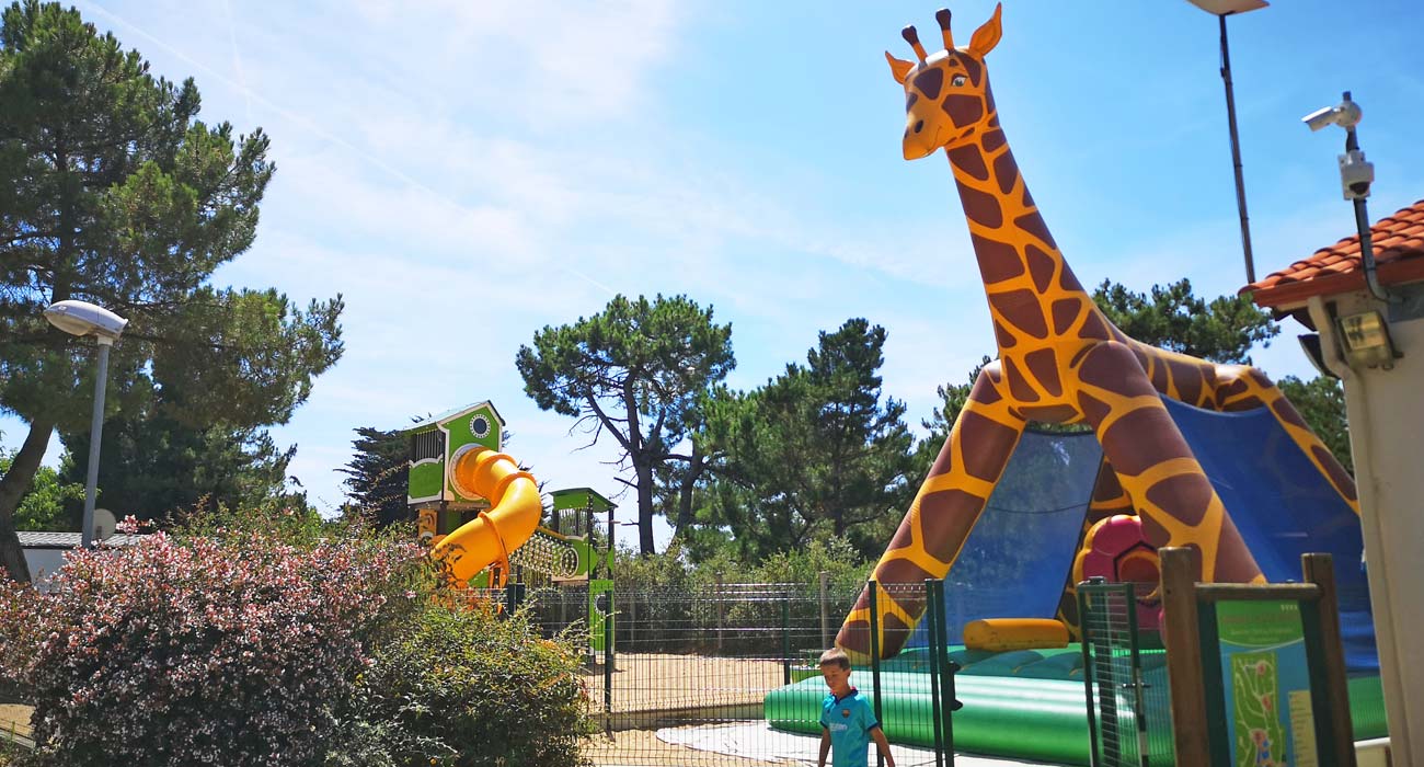 Opblaasbare constructie in de vorm van een giraf op de speelplaats van camping Le Clos des Pins in de Vendée