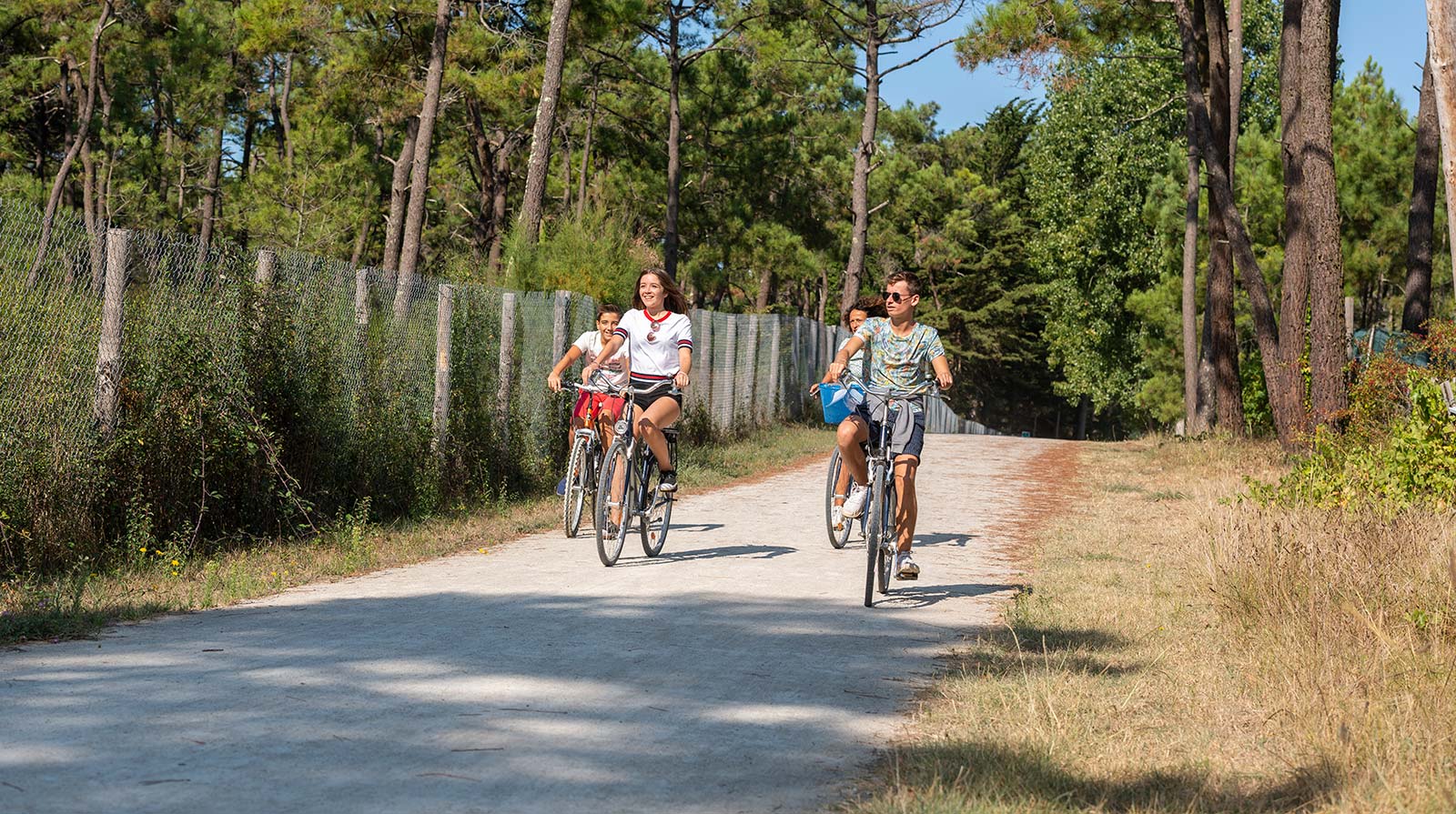 Campers fietsen op een pad naar het strand bij de camping in Saint-Hilaire