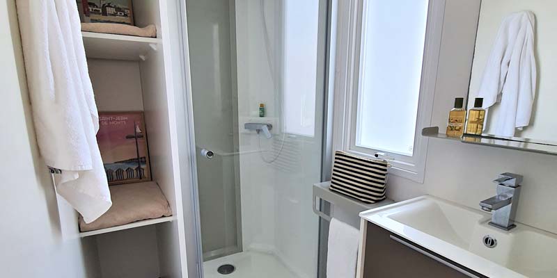 Wastafel en douche in de badkamer van een stacaravan te huur in Saint-Hilaire
