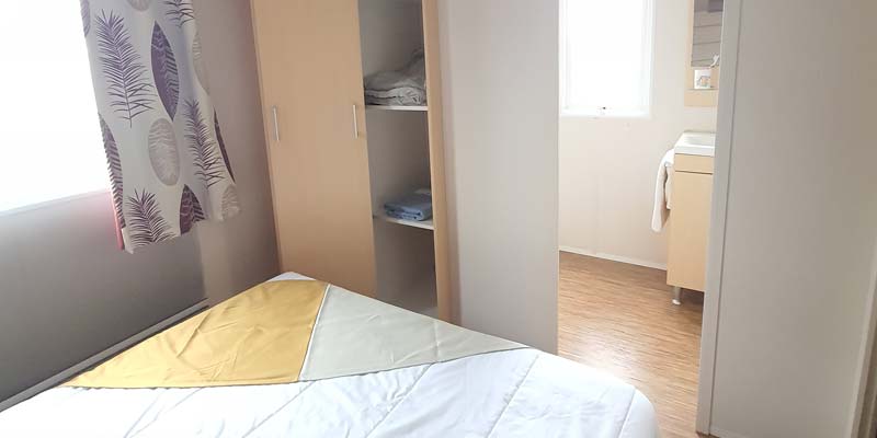 Slaapkamer met tweepersoonsbed en kast in een stacaravan in Saint-Hilaire