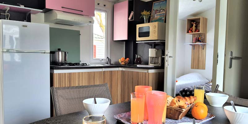 Kitchen area and table with fruits and orange juice in a mobile home in Vendée