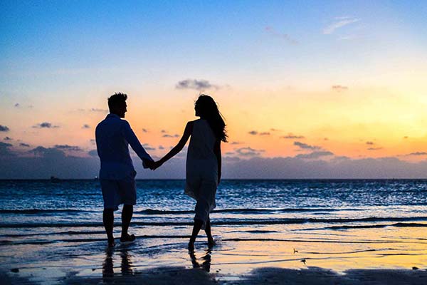Couple holding hands on Saint-Hilaire beach at dusk