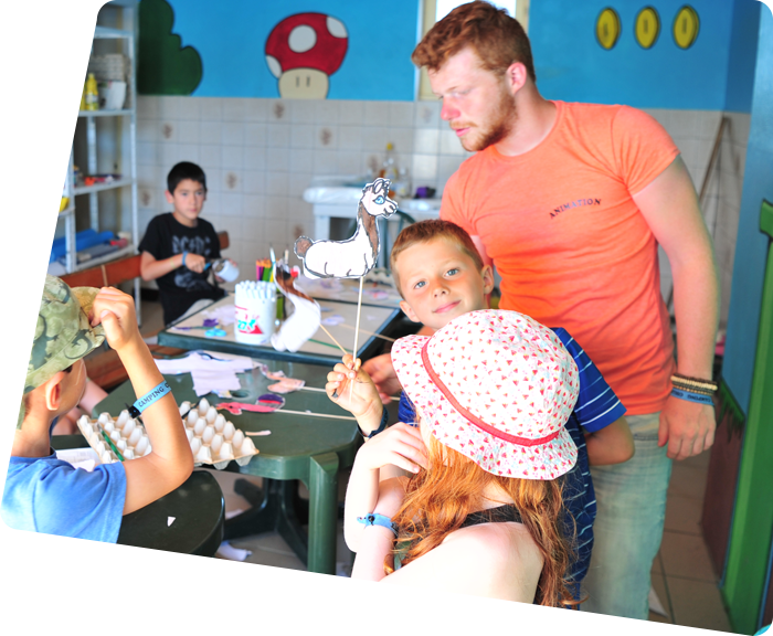 Red-haired entertainer playing with the children of the children's club at the campsite by the sea in Saint-Hilaire