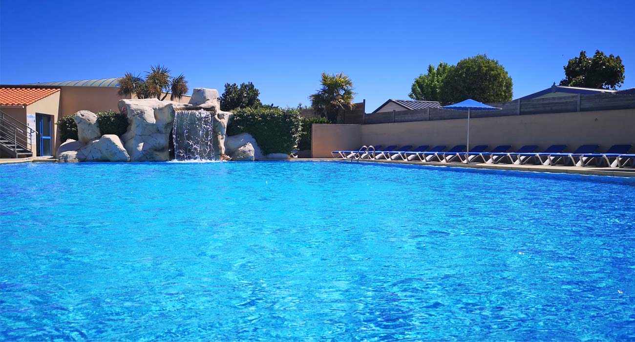 The pool of the outdoor aquatic area with its deckchairs at the campsite in Vendée