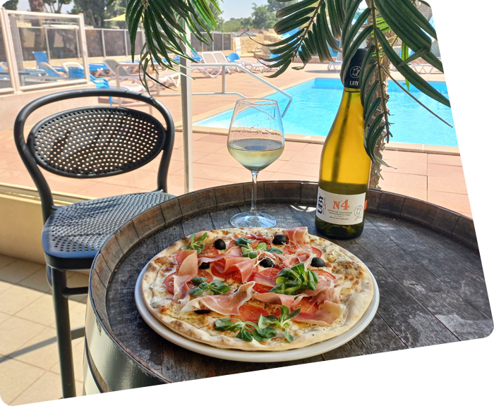 Pizza et bouteille de bin blanc sur la table de la pizzeria du camping à Saint-Hilaire