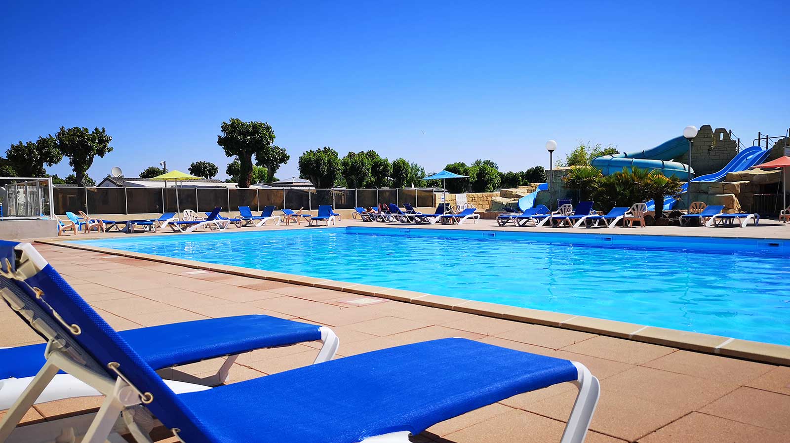 The pool of the outdoor aquatic area with its deckchairs at the campsite in Vendée