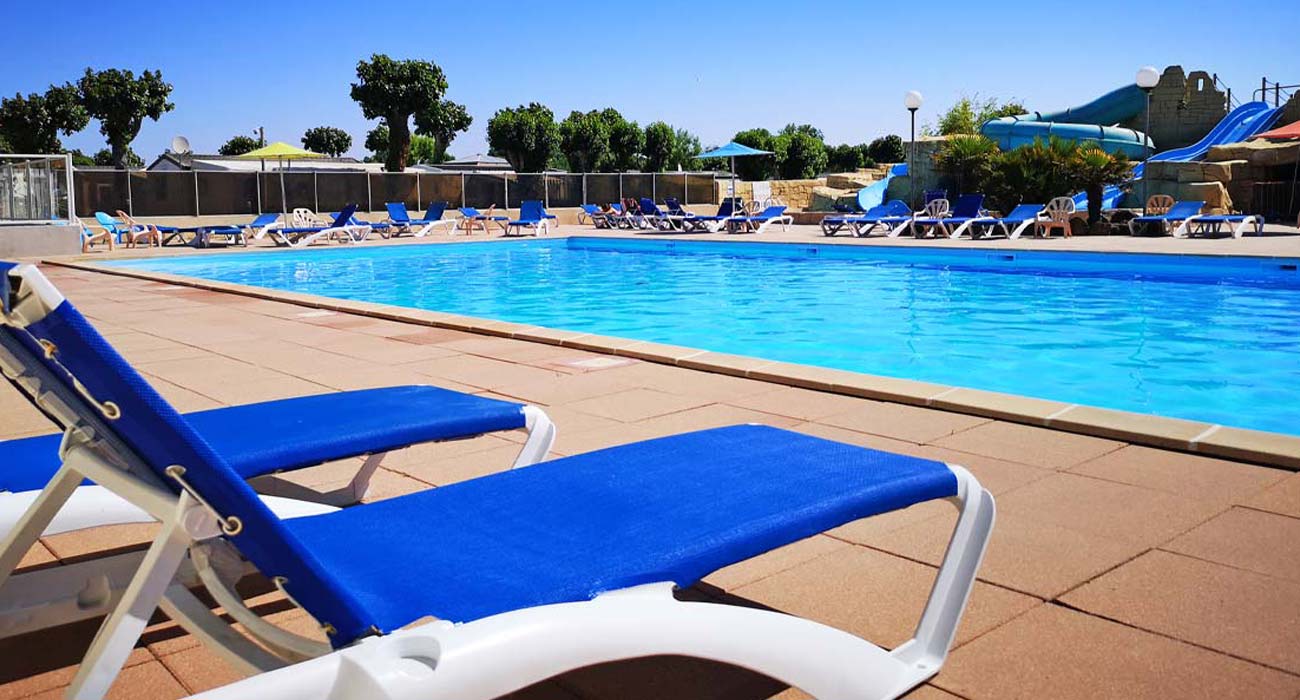 The pool of the outdoor aquatic area with its deckchairs at the campsite in Vendée