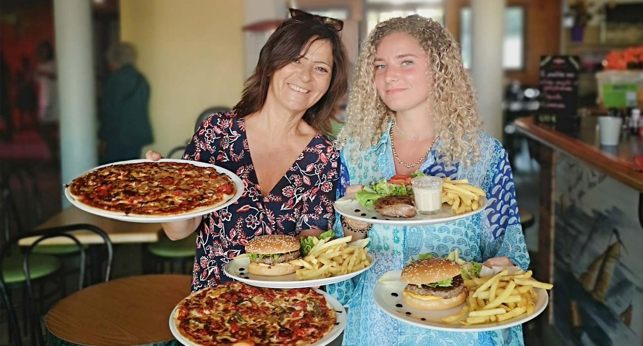 Jonge vrouwen houden borden vast met gerechten uit het campingrestaurant in Saint-Hilaire