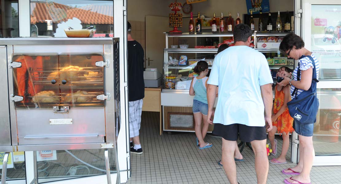 Campeurs devant des poulets rôtis et plats à emporter au camping La Prairie proche des plages en Vendée