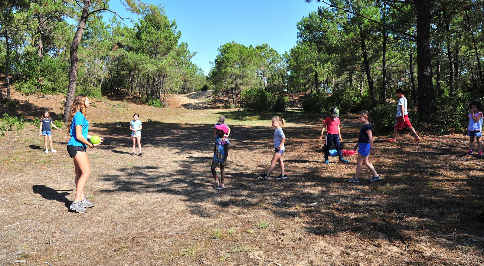 Children in a clearing with the children's club at Le Clos des Pins campsite in Saint-Hilaire