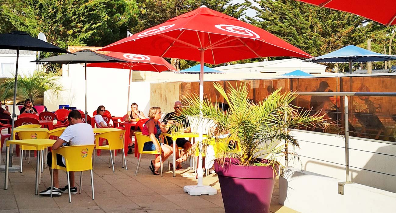 Het barterras met parasols op camping Le Clos des Pins in Saint-Hilaire