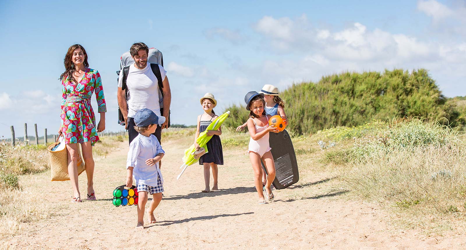 Familie van kampeerders op een zandpad dat aankomt op het strand van Saint-Hilaire