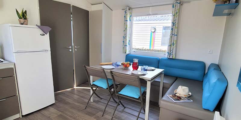 Salon avec chaises et canapé bleu dans un mobil-home ensoleillé à Saint-Hilaire