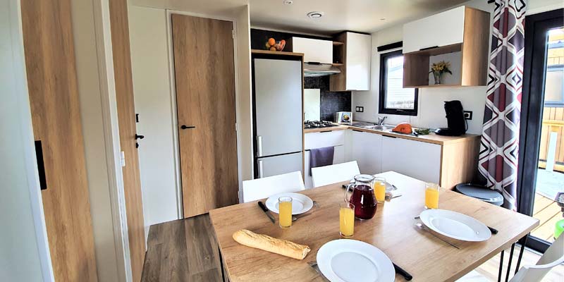 Table avec assiettes et cuisine dans un mobil-home au camping en Vendée