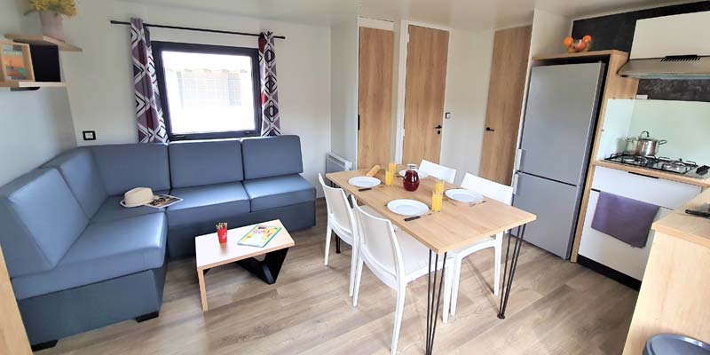 Pièce à vivre avec cuisine et table dans un mobil-home à louer à Saint-Hilaire