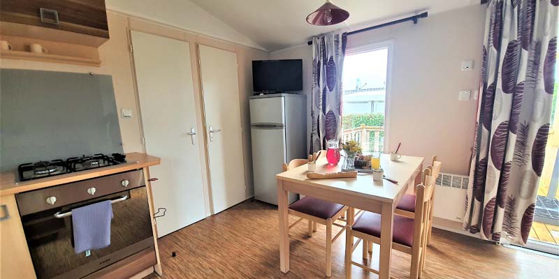 Living room with table and kitchen in a mobile home at the campsite in Saint-Hilaire