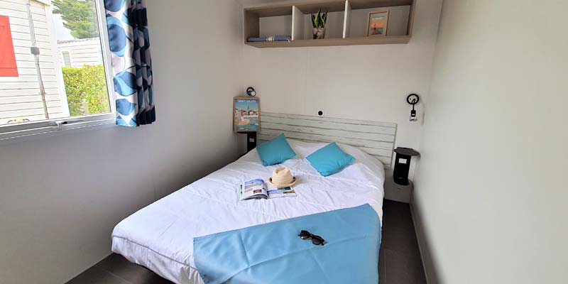 Book, straw hat and sunglasses on double bed of a mobile home in Saint-Hilaire