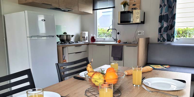 Kitchen area and table with fruits and orange juice in a mobile home in Vendée