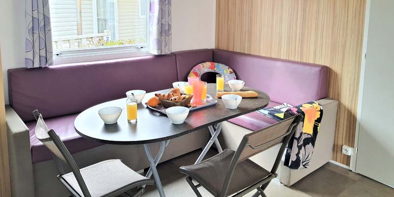 Salon avec chaises et canapé violet dans un mobil-home ensoleillé à Saint-Hilaire