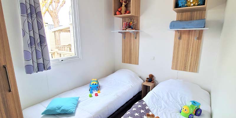 Chambre pour enfants avec deux lits et jouets dans un mobil-home en Vendée