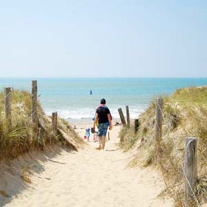 Campeur descendant à la plage proche du camping sur un chemin de sable en Vendée