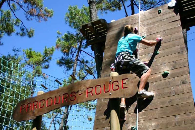 Jeune femme escaladant un mur au parc Feeling Forest en Vendée